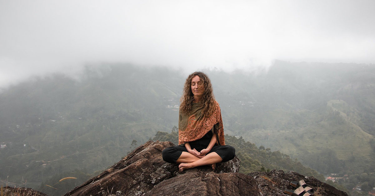 Friede im eigenen Herzen finden, Frau bei der Meditation auf Berg